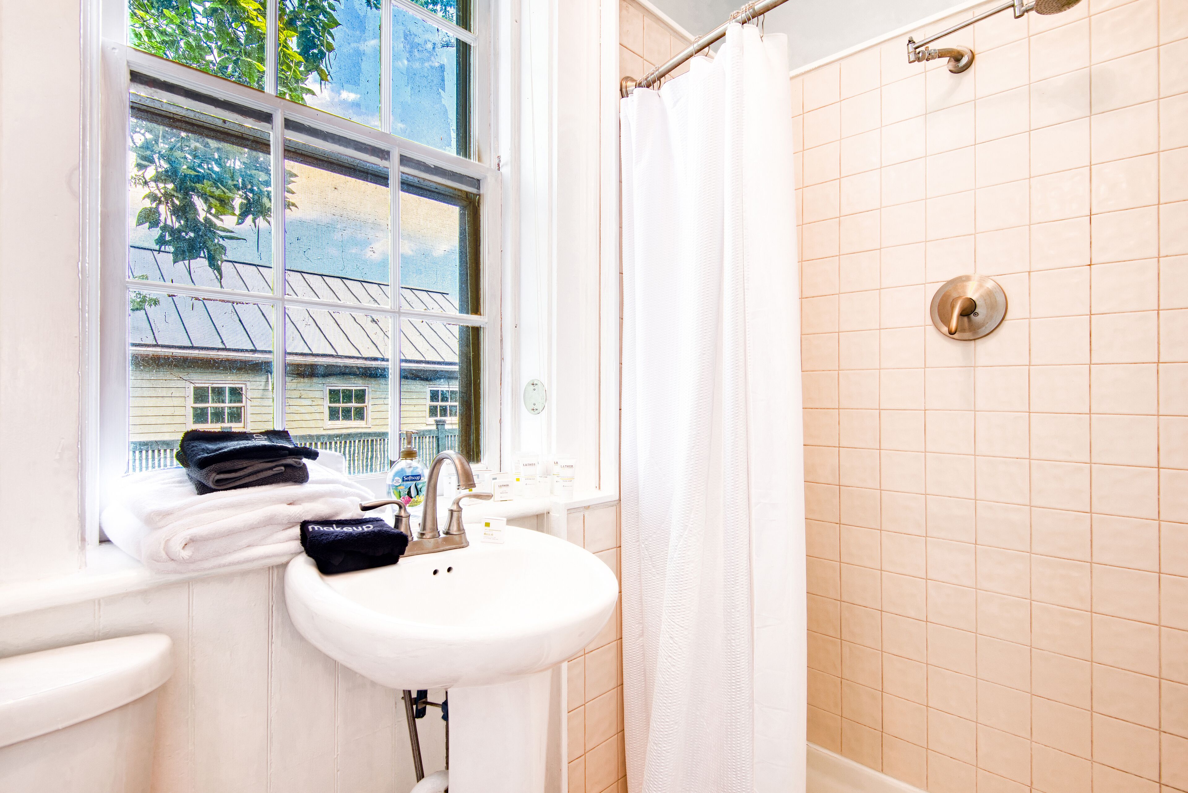 Ein Badezimmer mit Fenster, Waschbecken und Dusche.