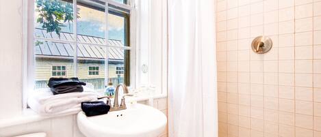 Ein Badezimmer mit Fenster, Waschbecken und Dusche.