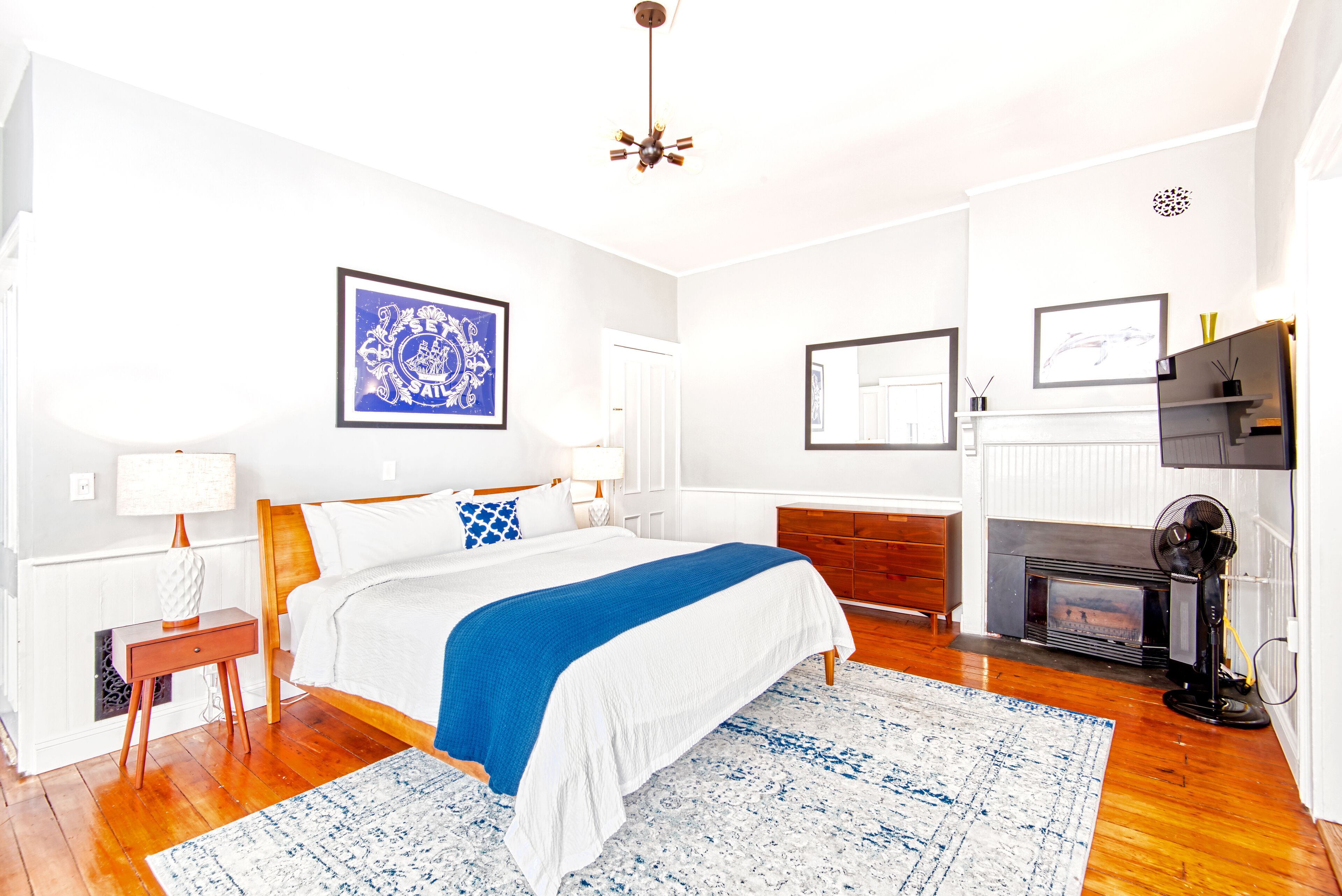 A bedroom with a bed, bedside tables, a fireplace, and a ceiling fan.