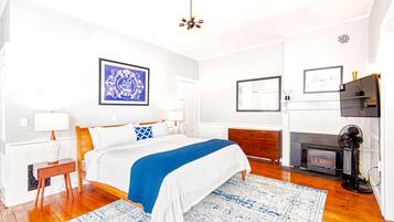 A bedroom with a bed, bedside tables, a fireplace, and a ceiling fan.