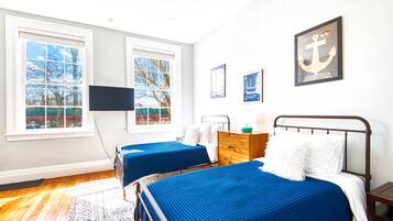 A bedroom with two beds, a TV, and artwork on the wall.