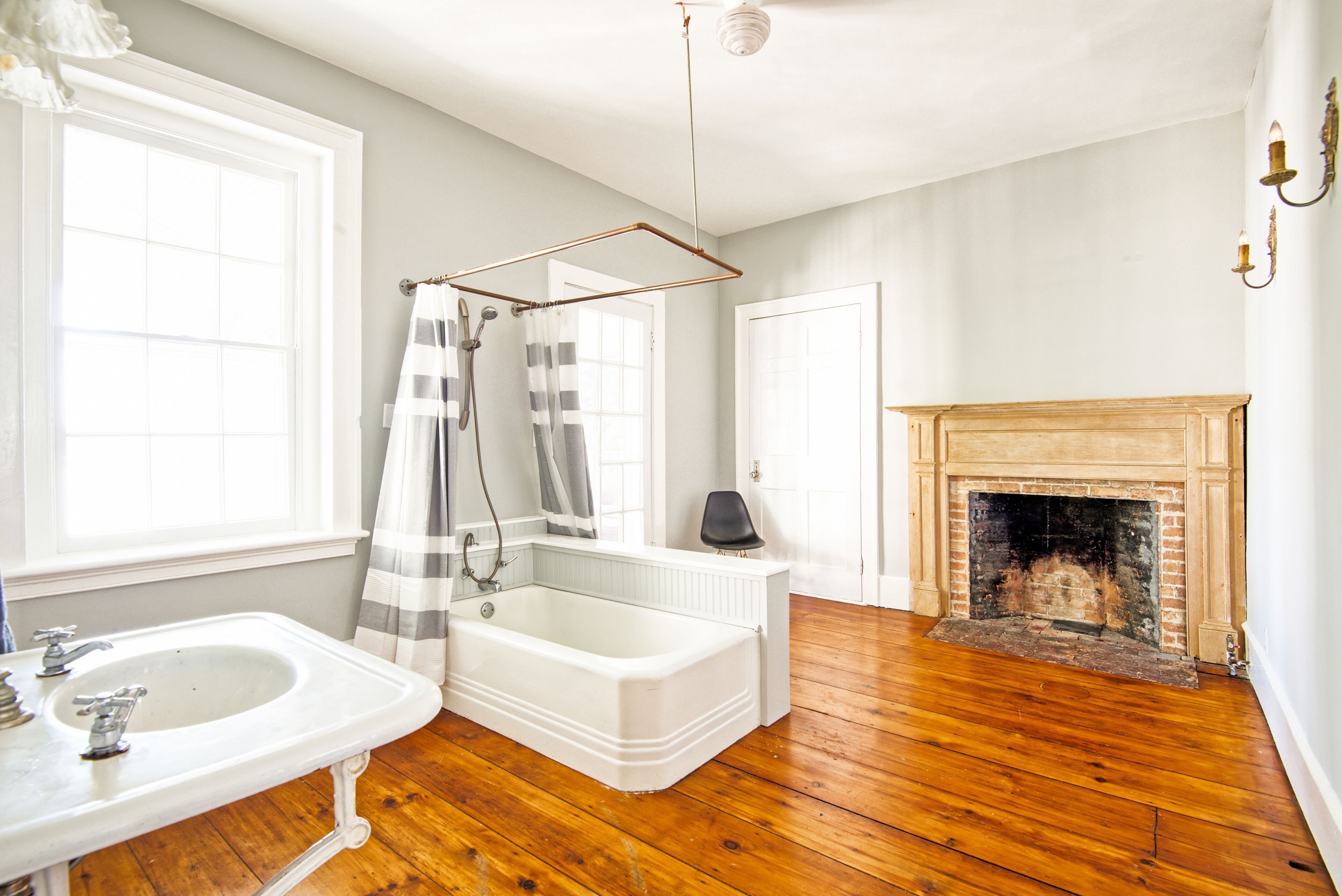 A bathroom with a bathtub, a sink, a shower curtain, and a fireplace.