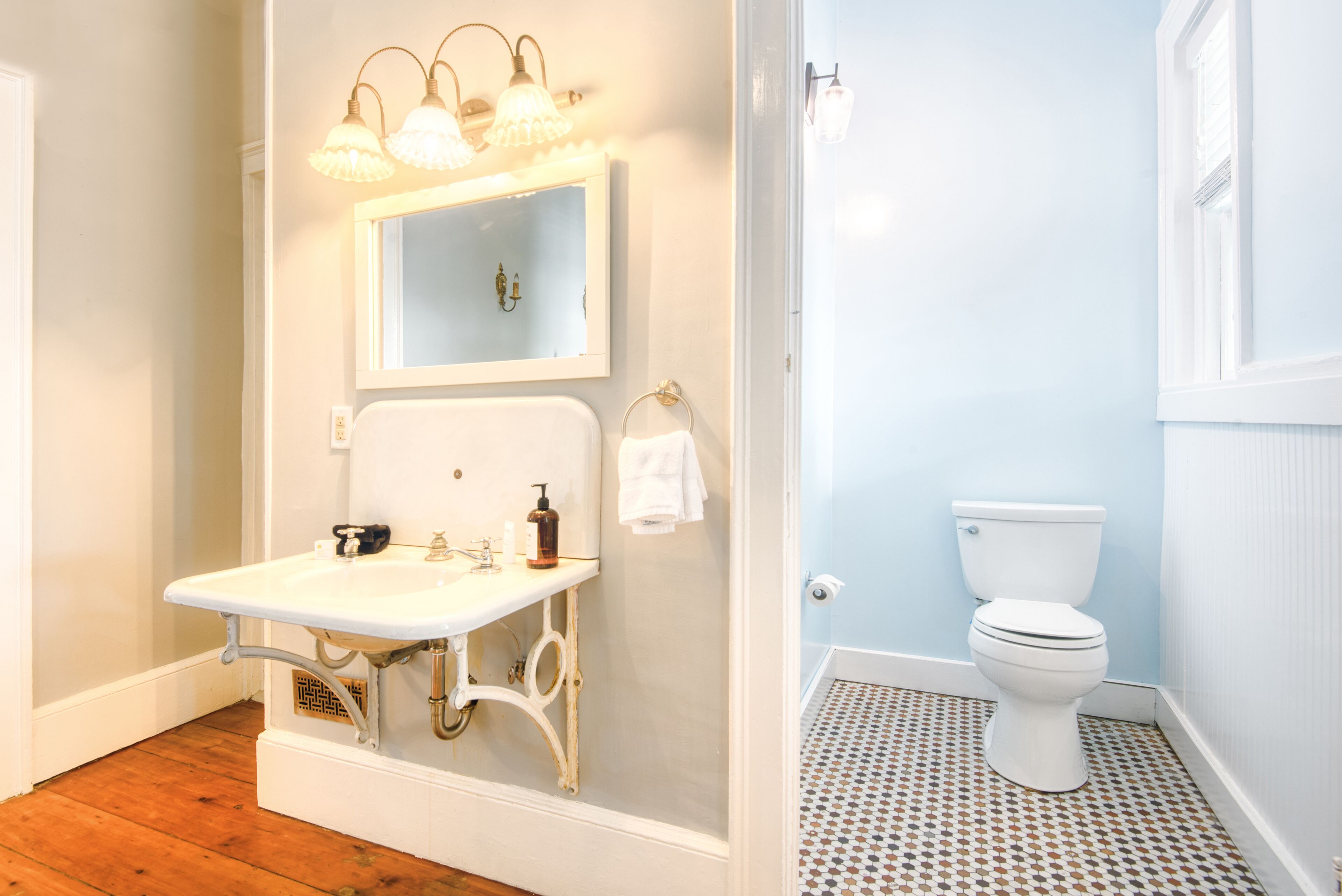 Une salle de bain avec un lavabo blanc, un miroir et des toilettes.