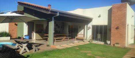 Relax in a spacious backyard with a covered patio, small pool, and well-maintained lawn.