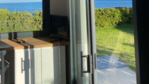 A modern kitchen with a large window, a wooden countertop, and a view of the sea. - Maison Les Pieds Dans Leau Large vue sur mer 20 m de la Plage Wide Sea View (Loctudy)