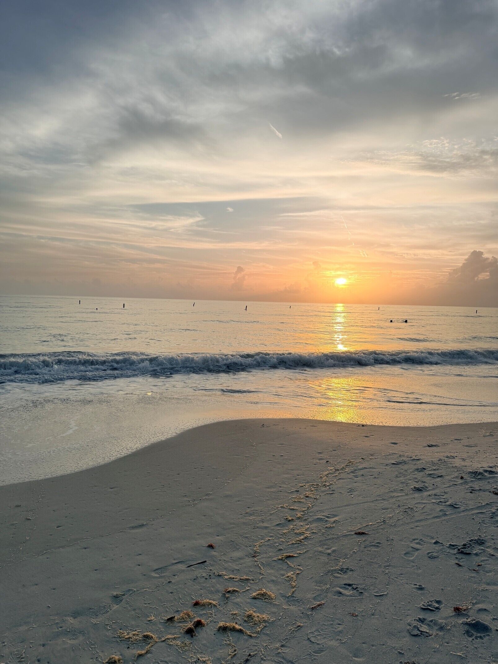 Une plage au coucher du soleil, avec des vagues et des empreintes de pas dans le sable.