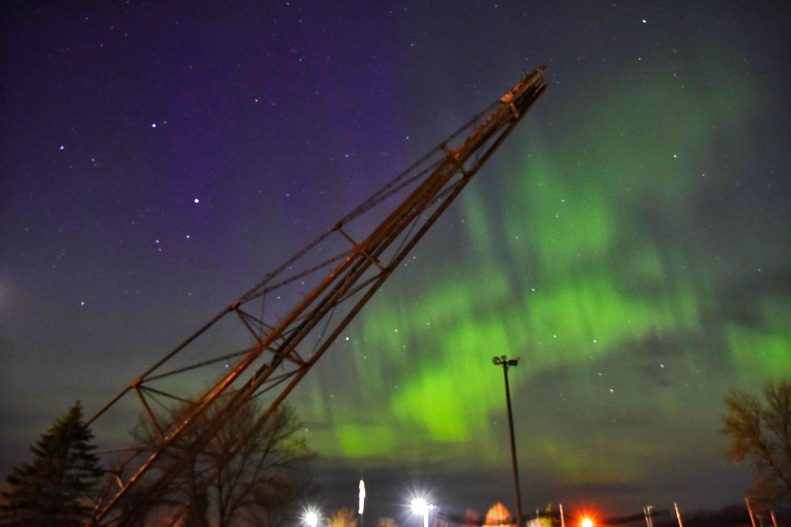 A crane against a night sky with visible stars and the aurora borealis.