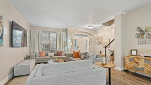 Un salón amplio con un conjunto de sofá gris, una mesa de centro y un mueble de madera.