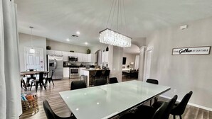 A modern kitchen with white cabinets, stainless steel appliances, and a chandelier. - Large 6BR w/ FREE water park and private pool (Kissimmee)