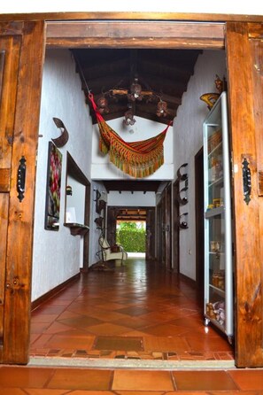 Enter a cozy hallway with a hammock suspended from the ceiling, leading to a glass door.