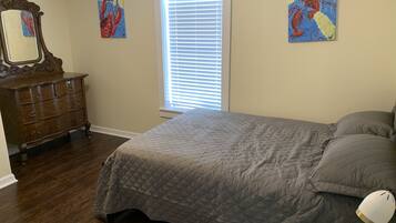 A bedroom with a bed, dresser, and artwork on the walls.