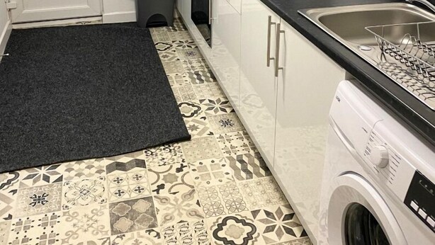 A compact kitchen with a washing machine, a sink, and a small trash bin. - Modern 1 Bedroom Flat in St Helens – Ideal for Relocation or Work Trips (St Helens)