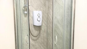 A glass-enclosed shower with a handheld showerhead and a control panel. - Modern 1 Bedroom Flat in St Helens – Ideal for Relocation or Work Trips (St Helens)