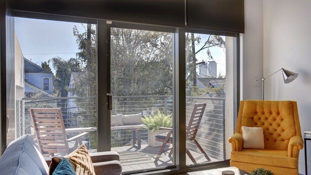 Ein modernes Wohnzimmer mit einer Schiebetür aus Glas, die auf eine Terrassensitzgruppe im Freien führt.