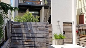 Ein modernes, zweistöckiges Haus mit Balkon, Holzzaun und Topfpflanze.