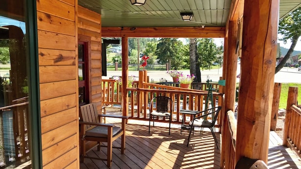 A wooden deck with outdoor seating and a view of a garden. - Mountain Peaks Inn, OLD BALDY MTN SUITE, Downtown Hill City (Hill City)