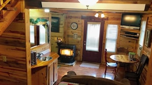 A cozy cabin interior with a wooden interior, a fireplace, a dining area, and a television. - Mountain Peaks Inn, OLD BALDY MTN SUITE, Downtown Hill City (Hill City)