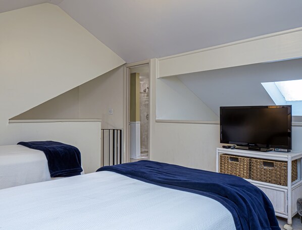 A bedroom with a bed, a television, and a small cabinet with baskets.