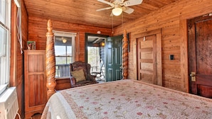 A wooden cabin bedroom with a bed, a chair, a ceiling fan, and a door. - Secluded Ridgetop Hideaway w/ Valley Views! (Menlo)
