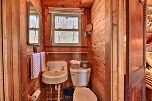 A wooden cabin bathroom with a window, a sink, a toilet, and a shower area. - Secluded Ridgetop Hideaway w/ Valley Views! (Menlo)
