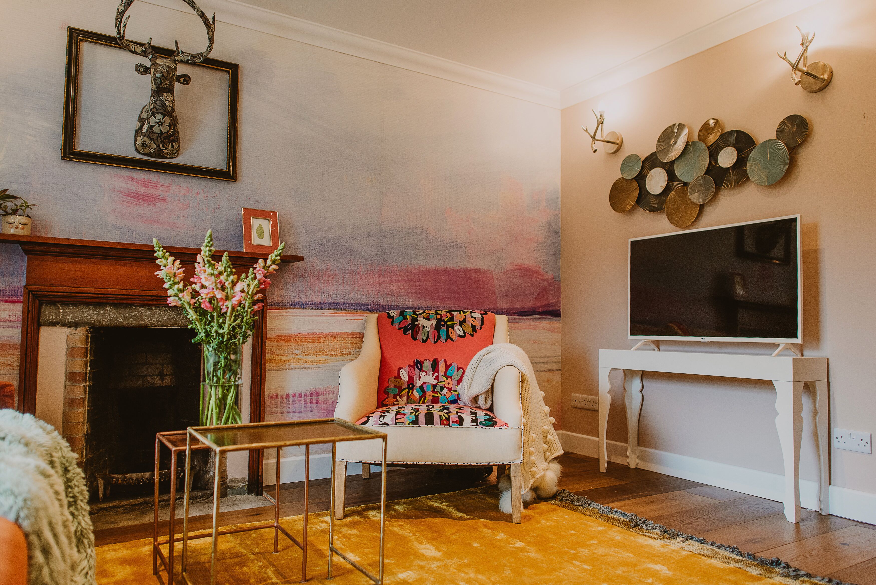 A living room with a fireplace, a television, and a decorative wall piece.
