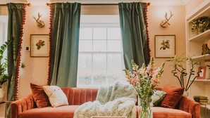 Een gezellige woonkamer met een rode bank, een witte salontafel en een vaas met bloemen.
