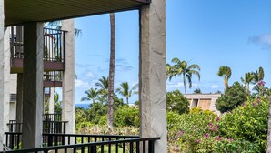 A hotel balcony with a view of palm trees and a building in the background.