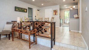 A dining area with a bamboo table and chairs, a sofa, and a staircase leading to another room.
