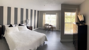 Ett sovrum med en säng, byrå, sängbord, lampa och en väggdekor med Musse Pigg.