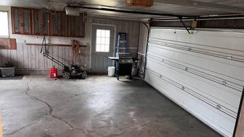 Un garage con pavimento in cemento, armadietti in legno, una porta e un basculante.
