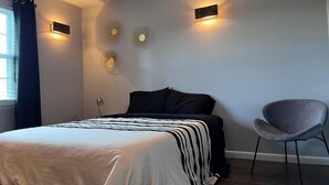 A bedroom with a bed, a chair, and wall-mounted fans. - Soldiers Home (West Lafayette)