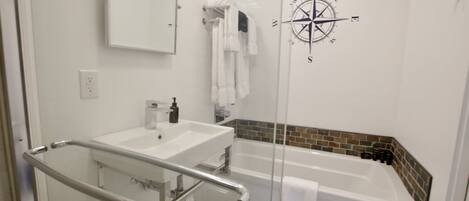 Un baño moderno con cabina de ducha de vidrio, un lavabo blanco y una bañera.