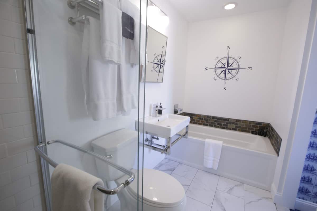 A modern bathroom with a glass shower enclosure, a white toilet, a sink, and a bathtub.