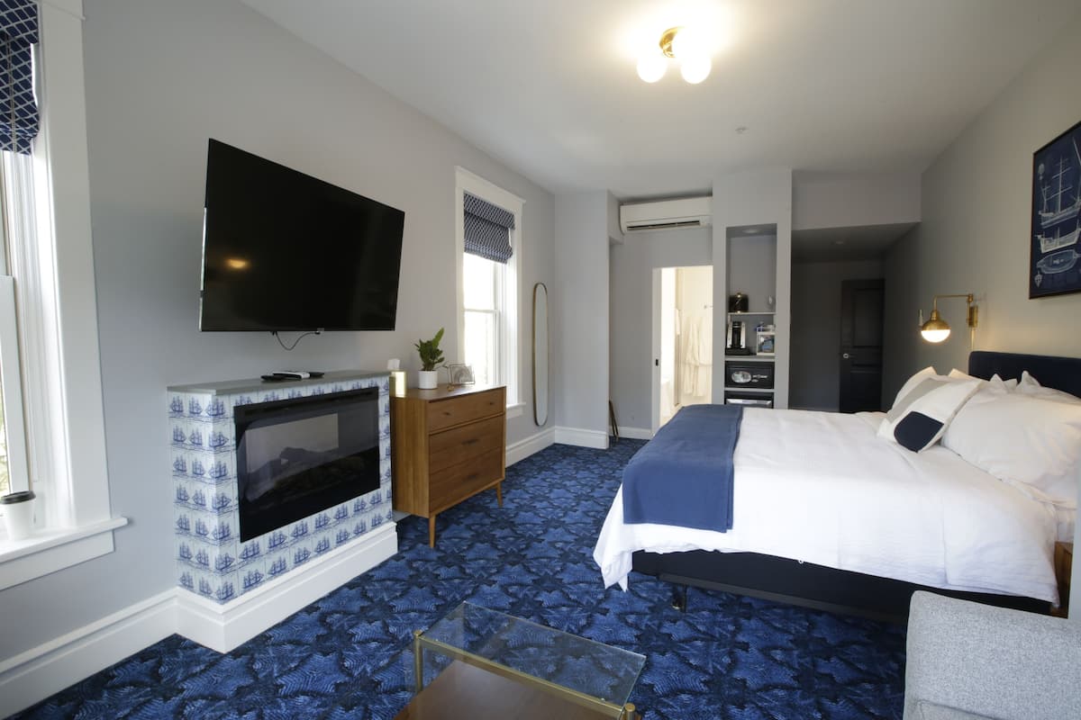 A bedroom with a bed, a television, a fireplace, and a mirror.
