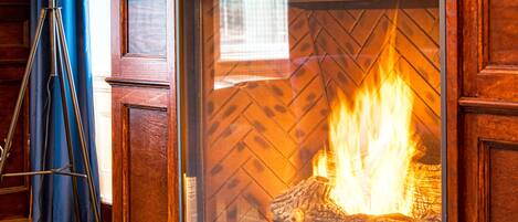 A fireplace with a ship model above it, a brass floor lamp, and a patterned rug on the floor.