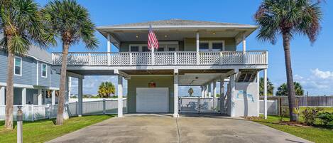 A two-story house with a covered front porch, a garage, and a flag.