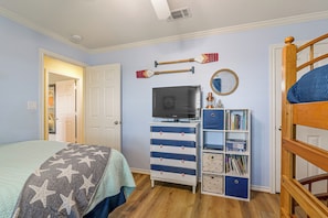 A bedroom with a bed, a dresser, a television, and a bunk bed. - Walk to Galveston Beach: Coastal Escape w/ Yard (Galveston)