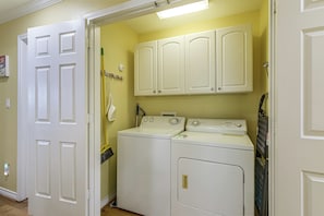 A laundry room with a washing machine, dryer, and cabinets. - Walk to Galveston Beach: Coastal Escape w/ Yard (Galveston)