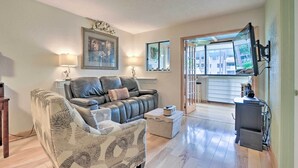 Un salon avec un canapé, un fauteuil et un téléviseur posé sur un meuble.