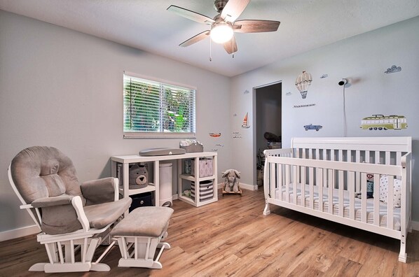 A baby room with a crib, rocking chair, and a play area with toys.