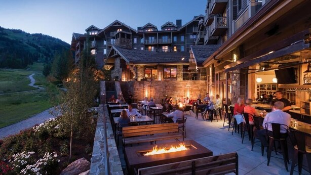 A lodge with outdoor seating and a bar, surrounded by a stone wall and a view of a valley. - 6/20 to 6/27 or 11/22 to 11/29, Four Seasons 3 BDRM, 3 Full Bath, Jackson Hole (Teton Village)