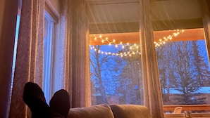 Una habitación con ventana, cortinas y una silla.