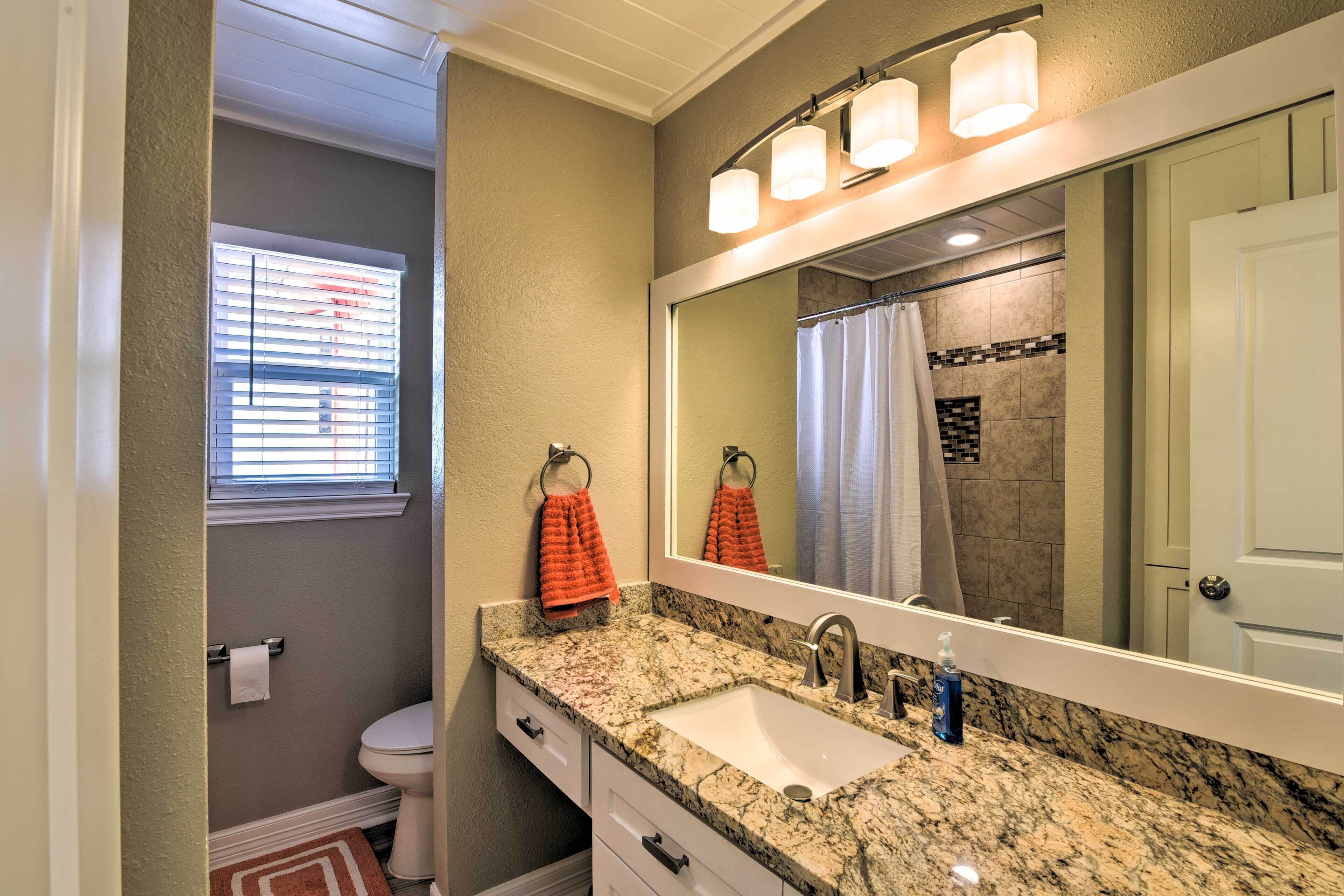 A bathroom with a granite countertop sink, a large mirror, and a shower curtain.