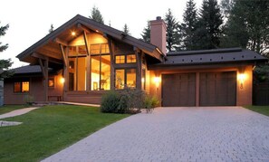 Ein modernes Haus mit einer großen Veranda, einer Garage und einem gepflegten Rasen.