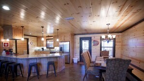 A wooden cabin interior with a kitchen, dining area, and bar.