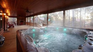 A hot tub on a wooden deck with a view of trees.