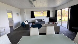 A spacious room with a large table and chairs, a sofa, and a ceiling fan. - Coopers Haven Beachfront House (Coopers Beach)