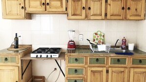 A kitchen with wooden cabinets, a gas stove, a blender, and a fruit basket. - Cozy & Lovely Studio! w/ DISNEY+, NETFLIX & More!! (zamora)