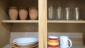 A shelf with pottery, glassware, and a mug. - Cozy & Lovely Studio! w/ DISNEY+, NETFLIX & More!! (zamora)