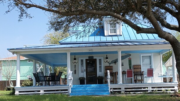 Een huis met een blauw dak, een veranda en een klein raam, nummer 212.